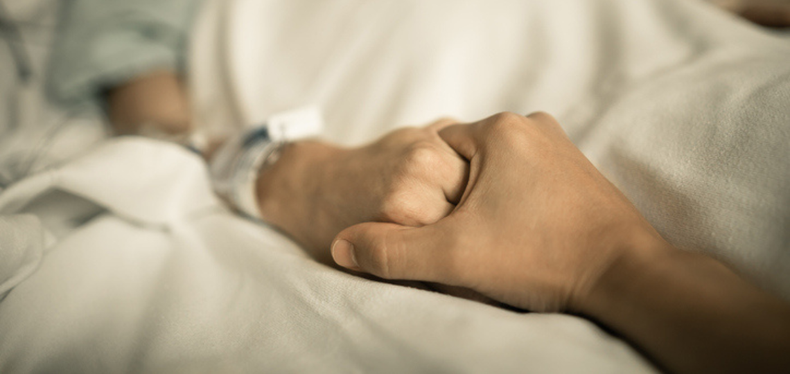 Imagen de una persona hospitalizada junto a un ser querido agarrándole la mano